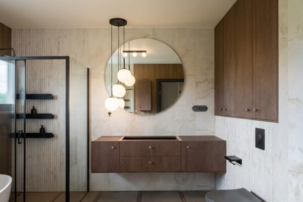 Zabudowa łazienki z wiszącą szafką i okrągłym lustrem De Morel