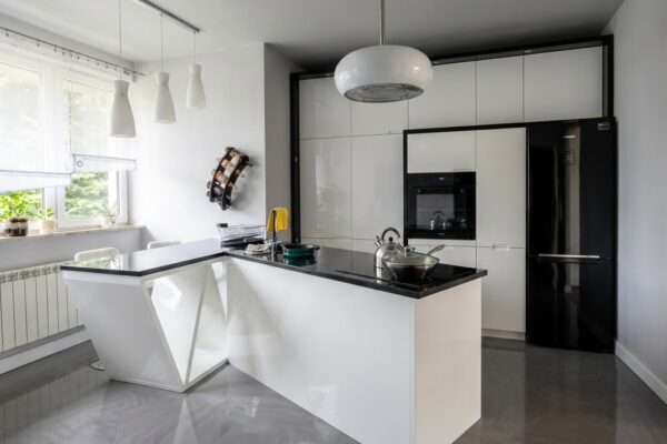Biała kuchnia w wysokim połysku z nowoczesną wyspą i czarnymi blatami Częstochowa
