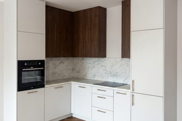 Kuchnia narożna z marmurowym blatem i wiszącymi szafkami w kolorze orzecha De Morel